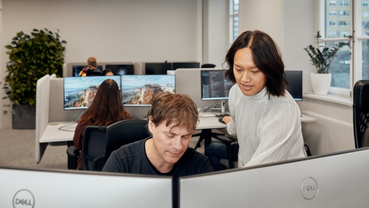 A woman and a man looking at something on a computer screen in a office landscape