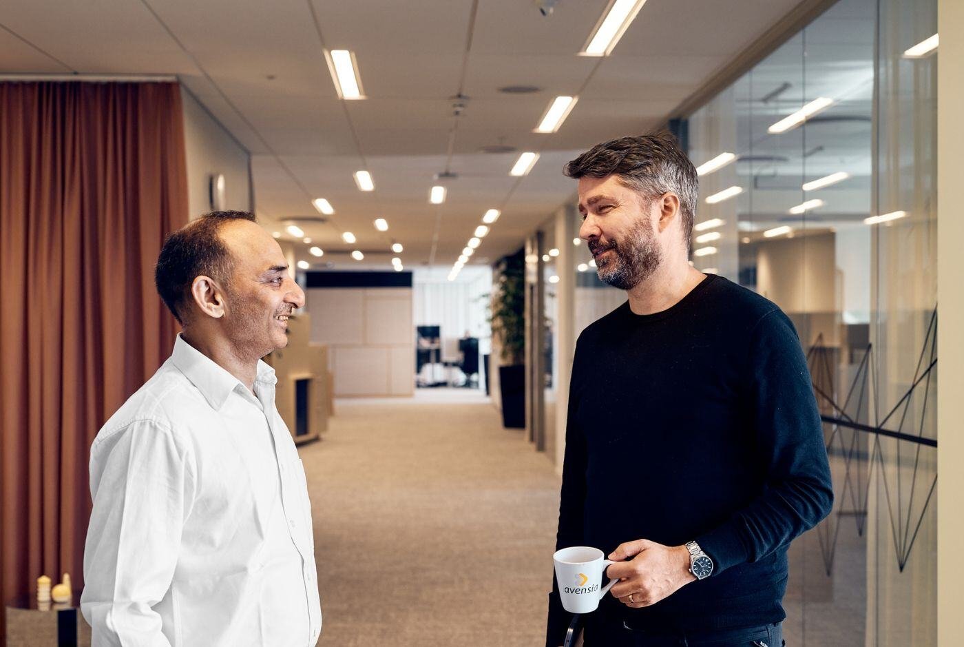 Two male colleages facing each other, chatting and smiling
