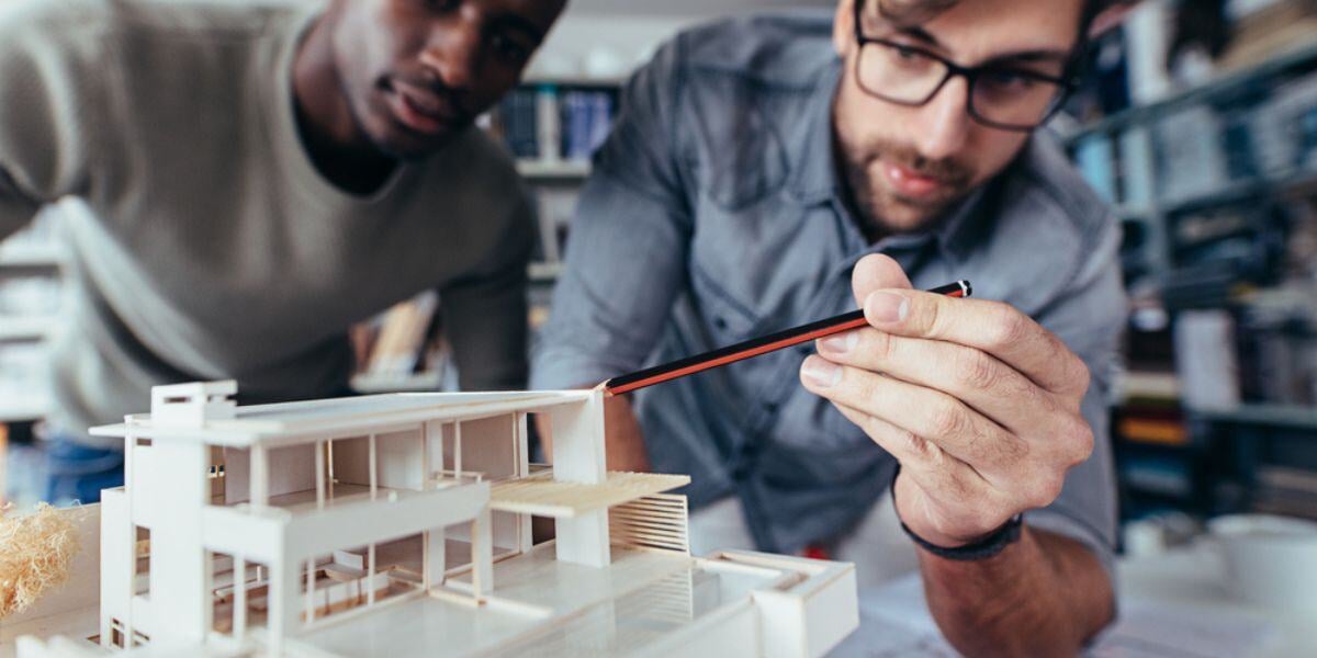 Two men looking at a model figure of a building