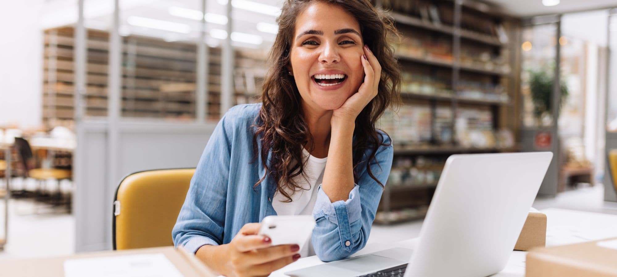 A woman sitting by her desk smiling into the camera