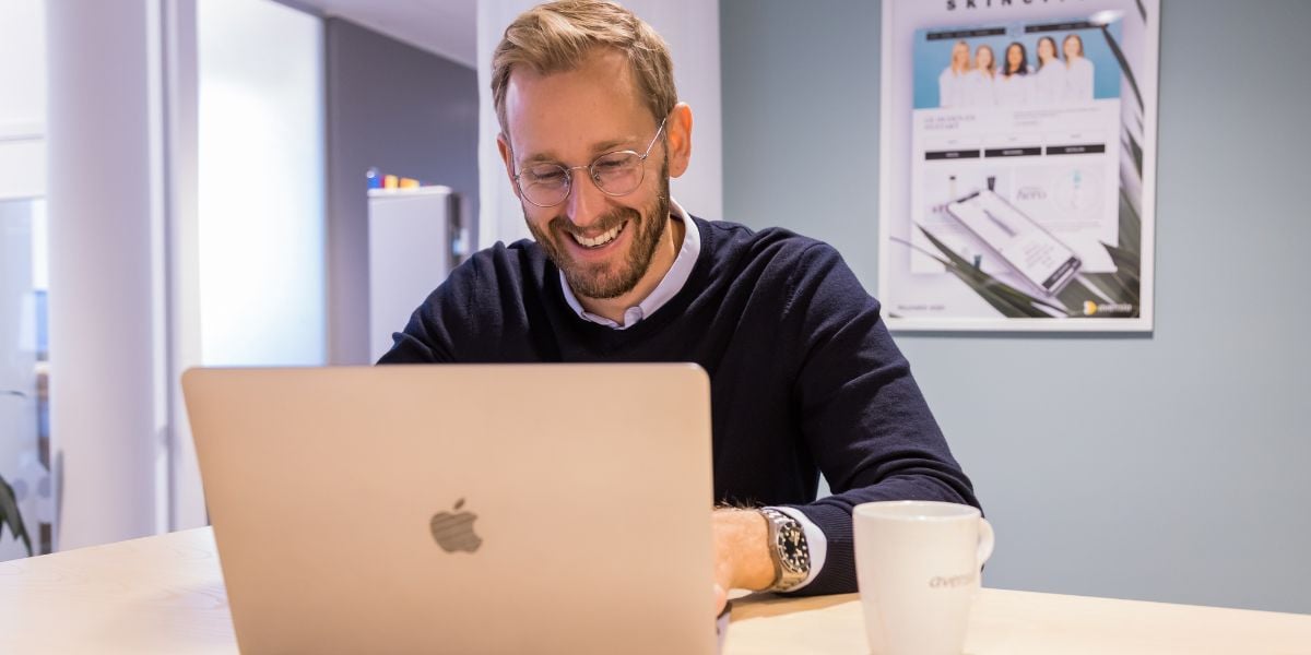 A man reading something in his laptop smiling