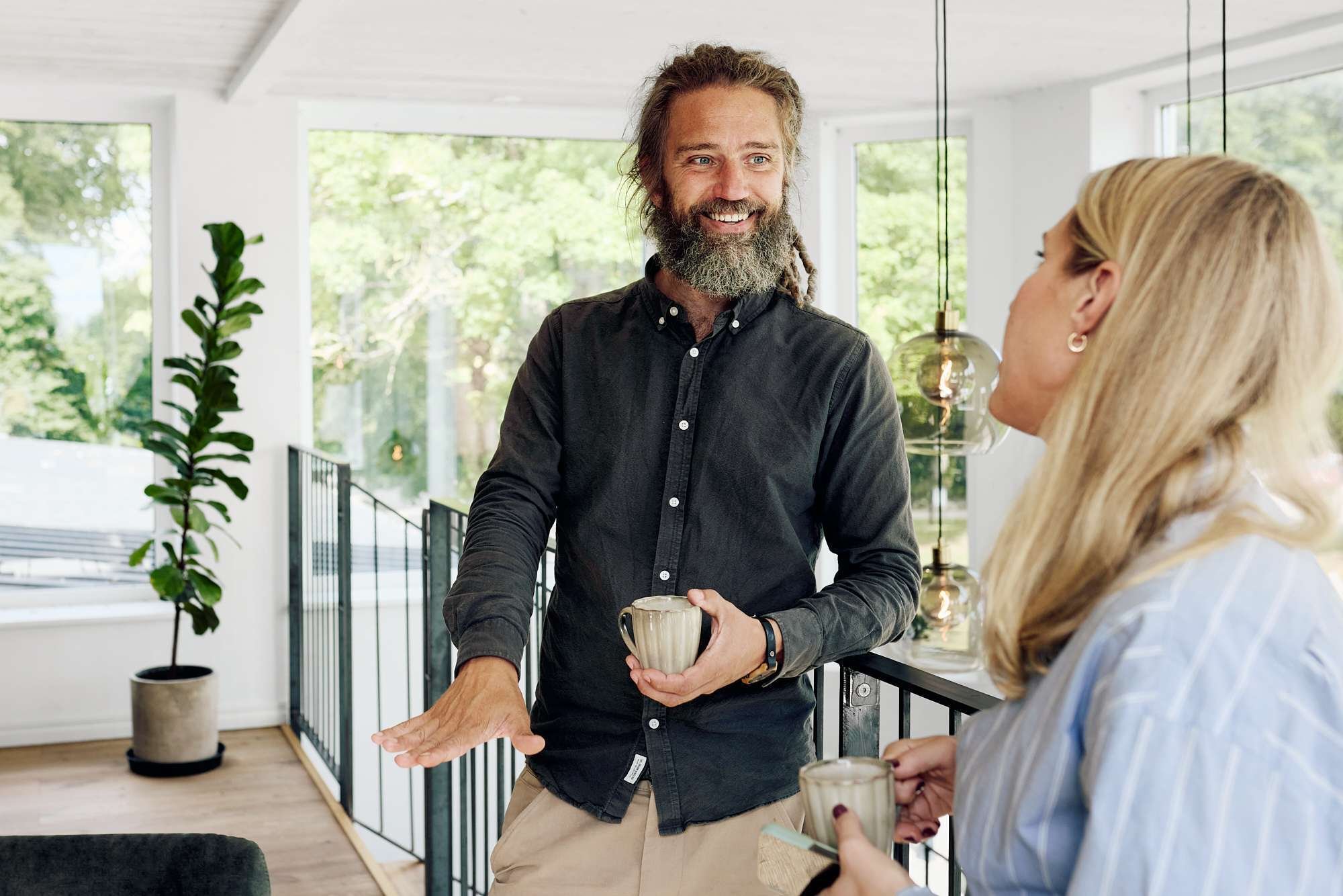 A female and a male co-worker chatting and drinking coffee