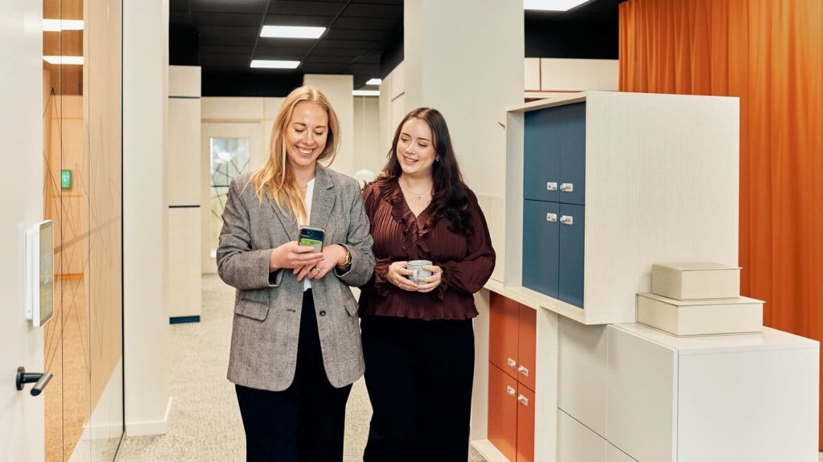Two female colleagues looking at a mobile phone smiling