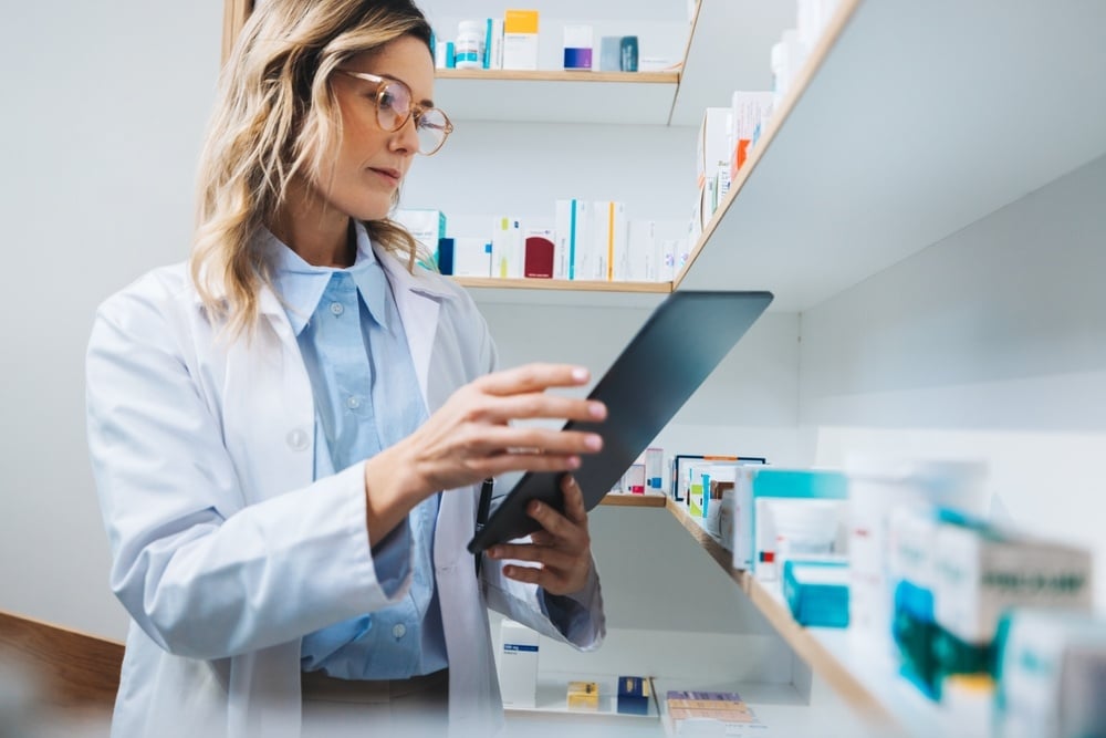 A woman working in a pharmacy looking at an ipad
