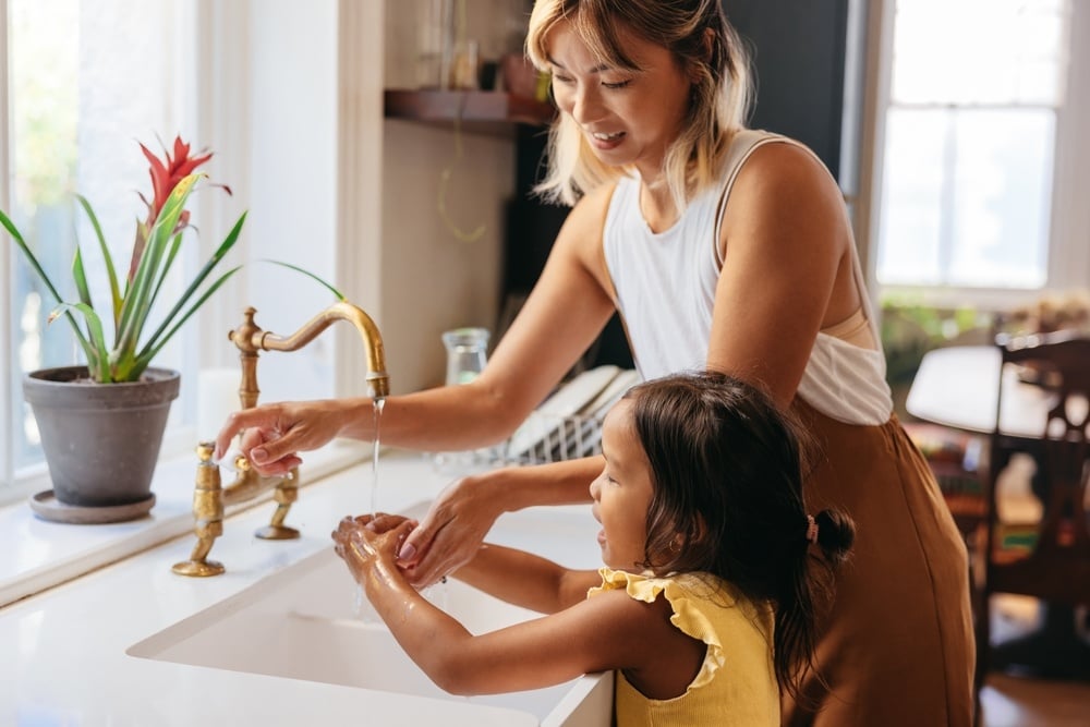 A mother helping her daughter washing her hands