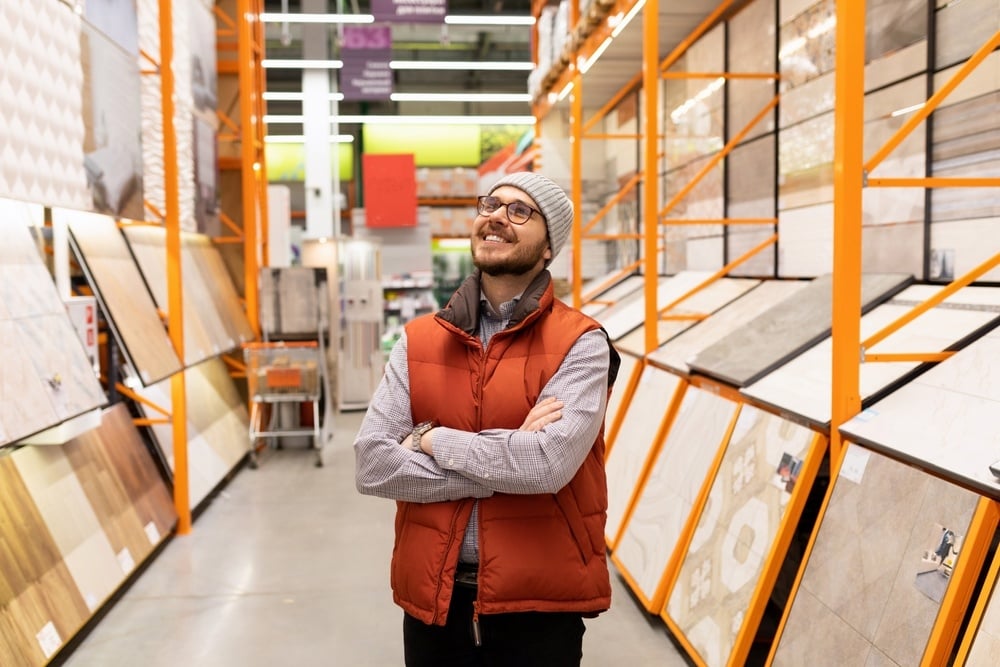 A man standing inside a hardware store, thinking